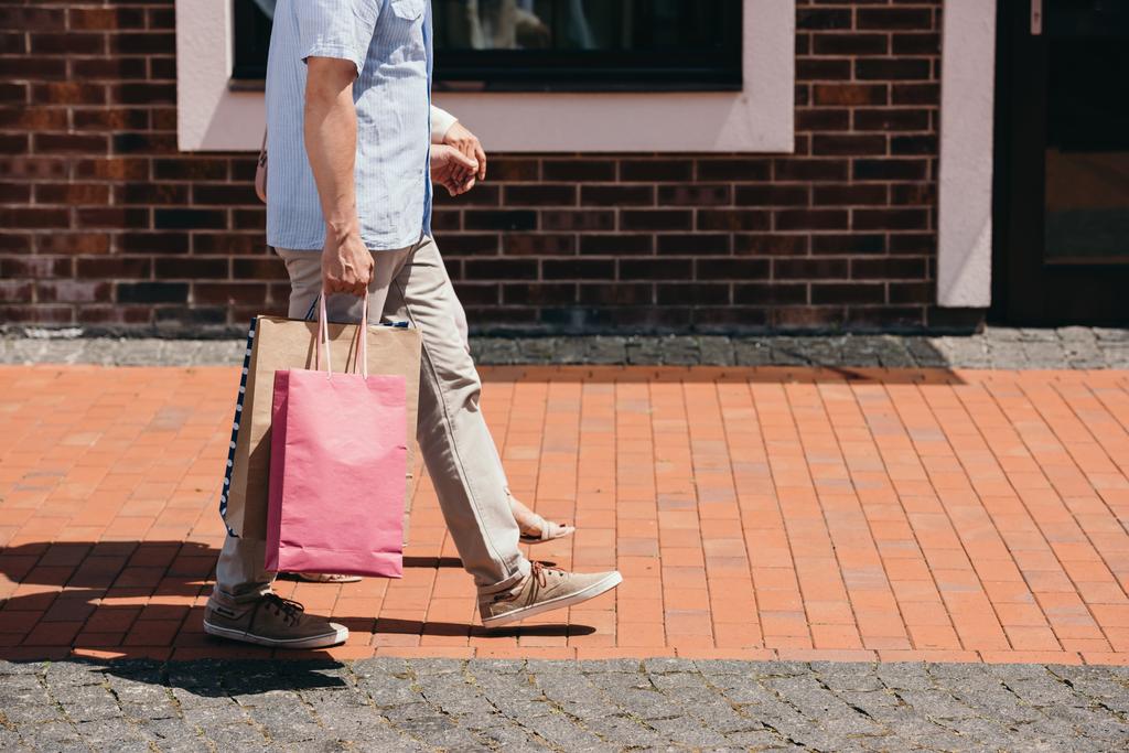 image recadrée de couple marchant avec des sacs à provisions dans la rue
 - Photo, image