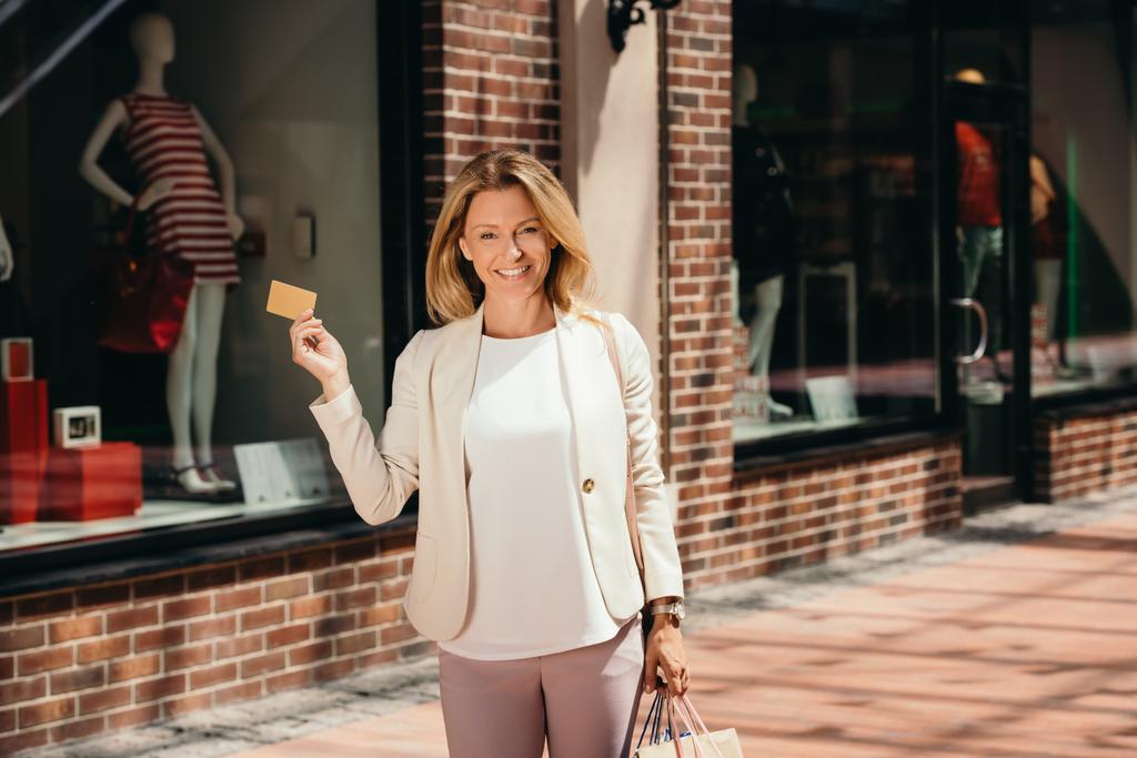atractiva mujer con tarjeta de crédito y bolsas de compras en la calle
 - Foto, imagen