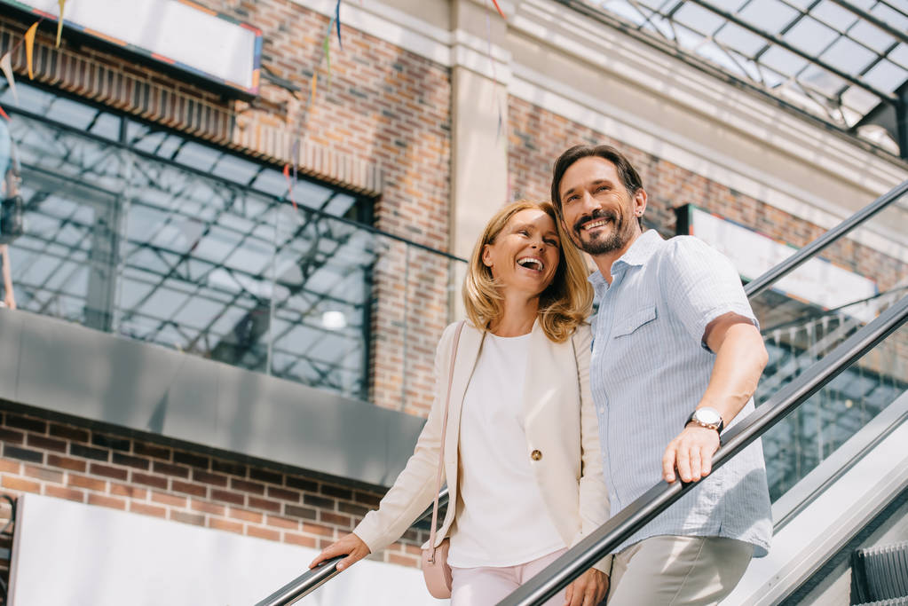 Lachendes erwachsenes Paar auf Rolltreppe in Einkaufszentrum - Foto, Bild