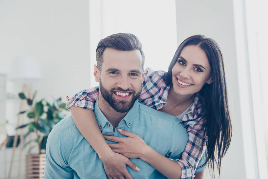 Head shot portrait of lovely cheerful couple in casual shirts with modern hairdo enjoying time together indoor looking at camera. Weekend vacation holiday concept - Photo, Image