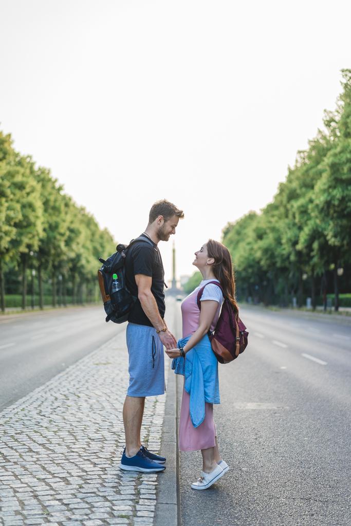 vista laterale della coppia che si tiene per mano e si guarda in strada a Berlino, Germania
 - Foto, immagini