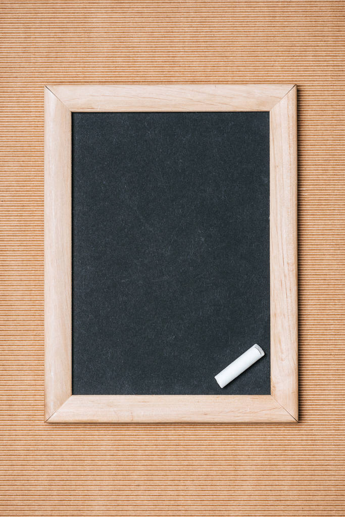 felülnézet üres tábla és kréta darab barna háttér  - Fotó, kép