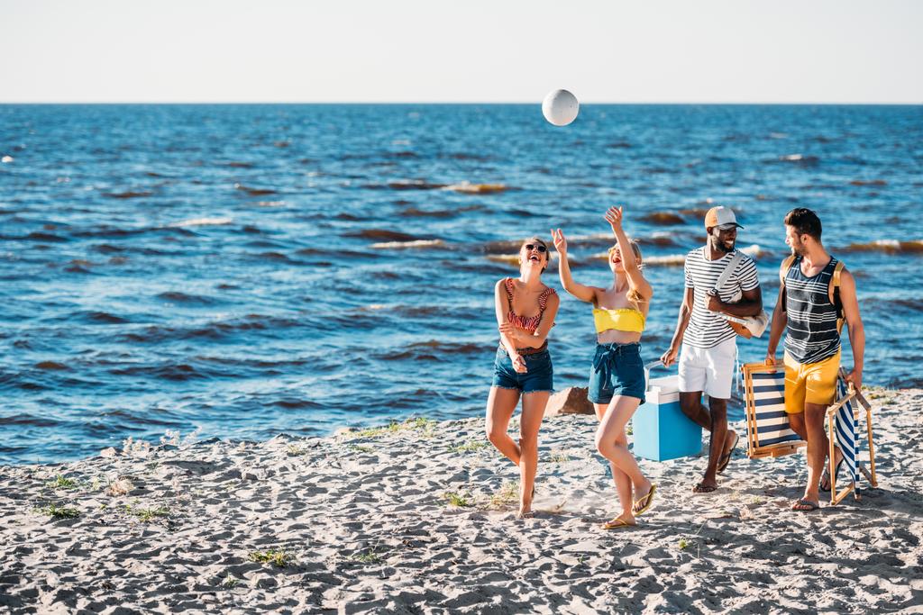 Happy mladých mnohonárodnostní přátelé hrát s míčem při chůzi na písečné pláži - Fotografie, Obrázek