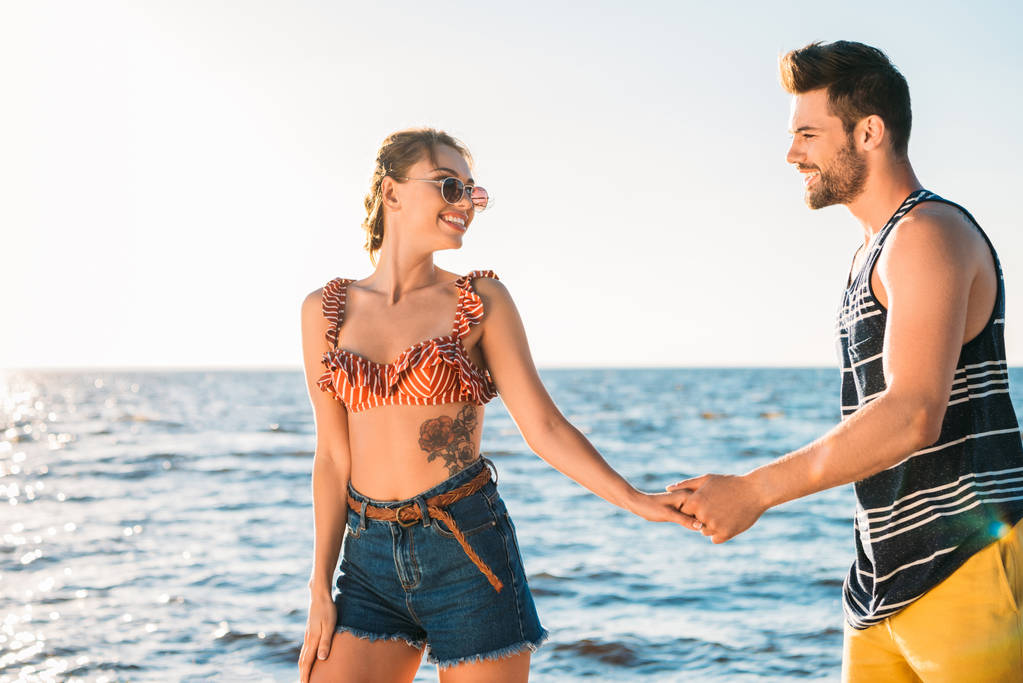 美しい幸せな若いカップル手を繋いで、一緒に海岸を歩いて  - 写真・画像