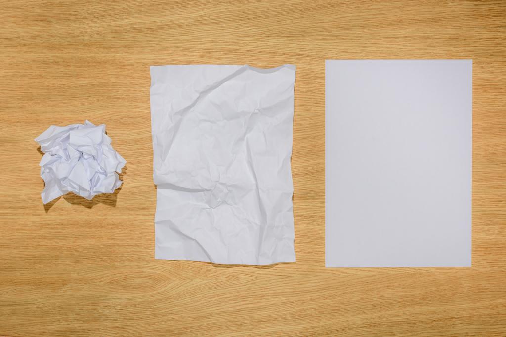 bovenaanzicht verfrommeld papier en blanco wit papier op houten tafel  - Foto, afbeelding