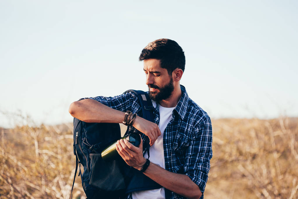 ハイカーの男性は、バックパックで水のボトルを置きます。ハイキング概念冒険を探索 - 写真・画像