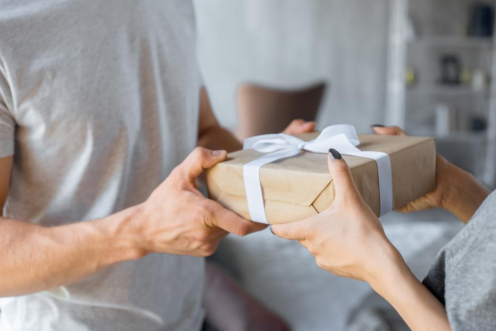 partial view of man presenting wrapped gift to girlfriend at home - Photo, Image