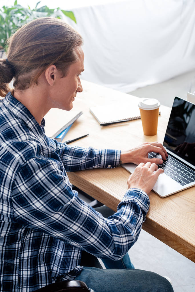 vue grand angle de l'homme en utilisant un ordinateur portable avec écran blanc sur le lieu de travail
 - Photo, image
