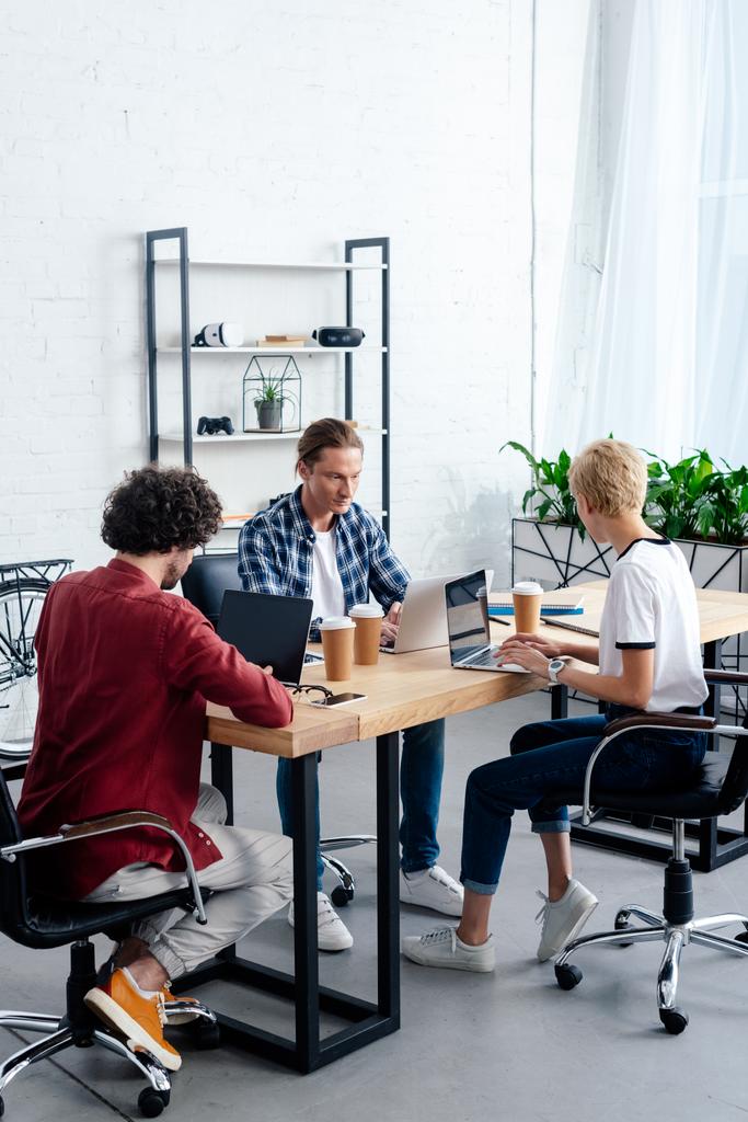 zespół młodych biznesowych za pomocą laptopów siedząc razem w miejscu pracy  - Zdjęcie, obraz