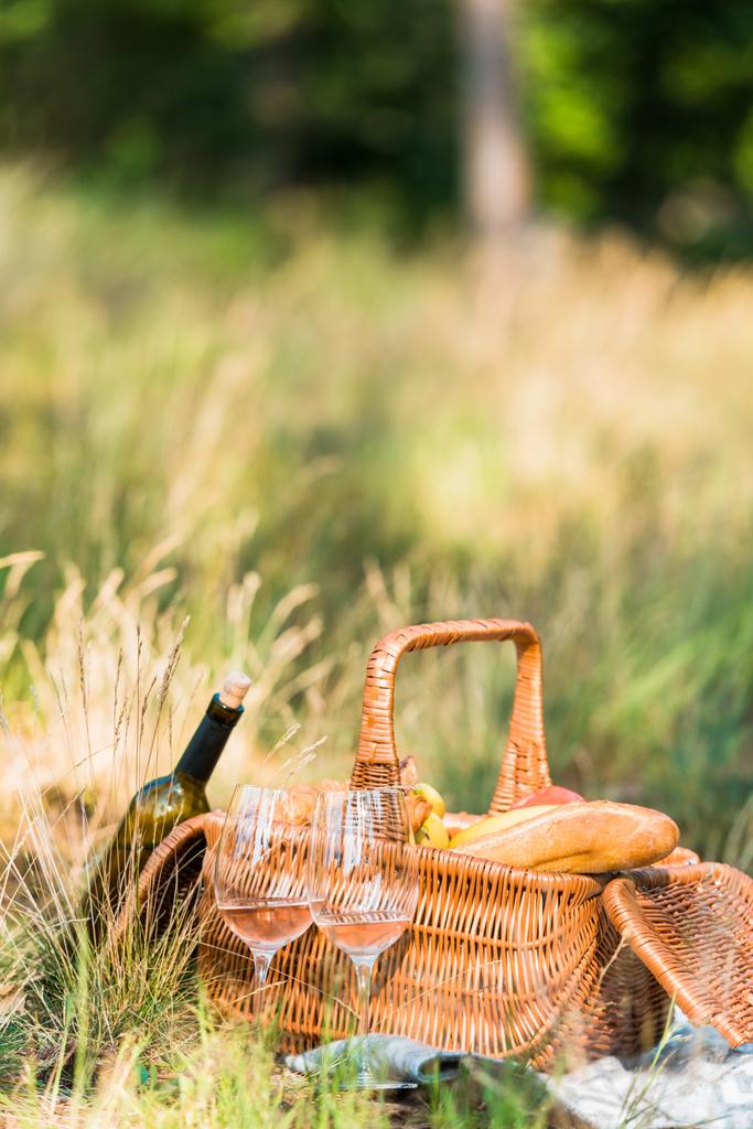ワインボトル、グラス、ピクニックでの芝生の上のパンのバスケット - 写真・画像