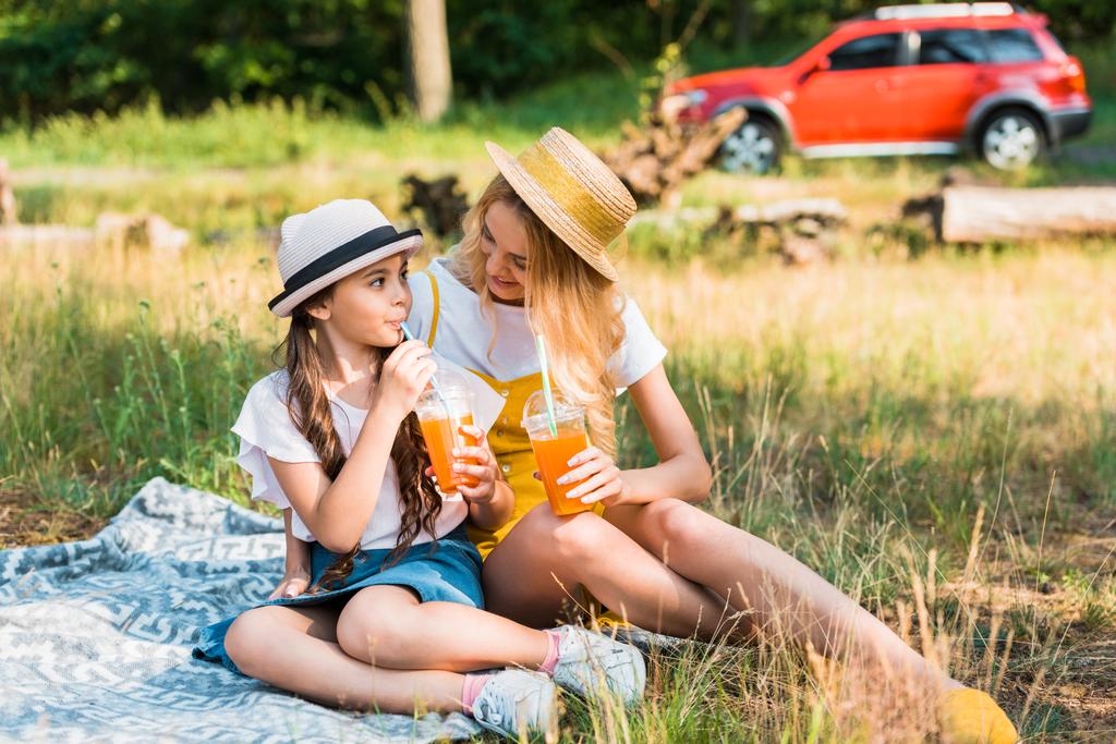 madre e hija bebiendo jugo en el picnic
 - Foto, imagen