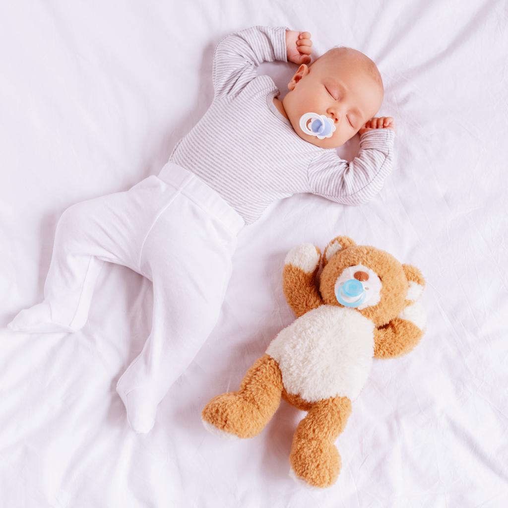 high angle view of adorable little boy with baby dummy sleeping with teddy bear  - Photo, Image