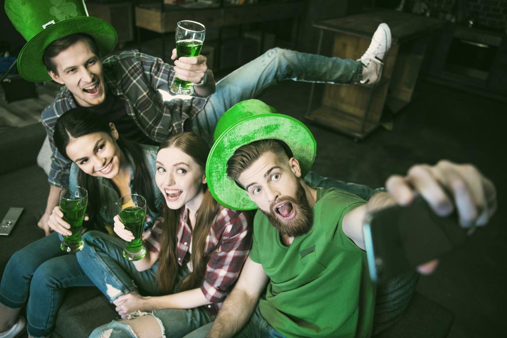 vista de ángulo alto del grupo de amigos felices con cerveza haciendo selfie en el día de San Patricio
 - Foto, imagen