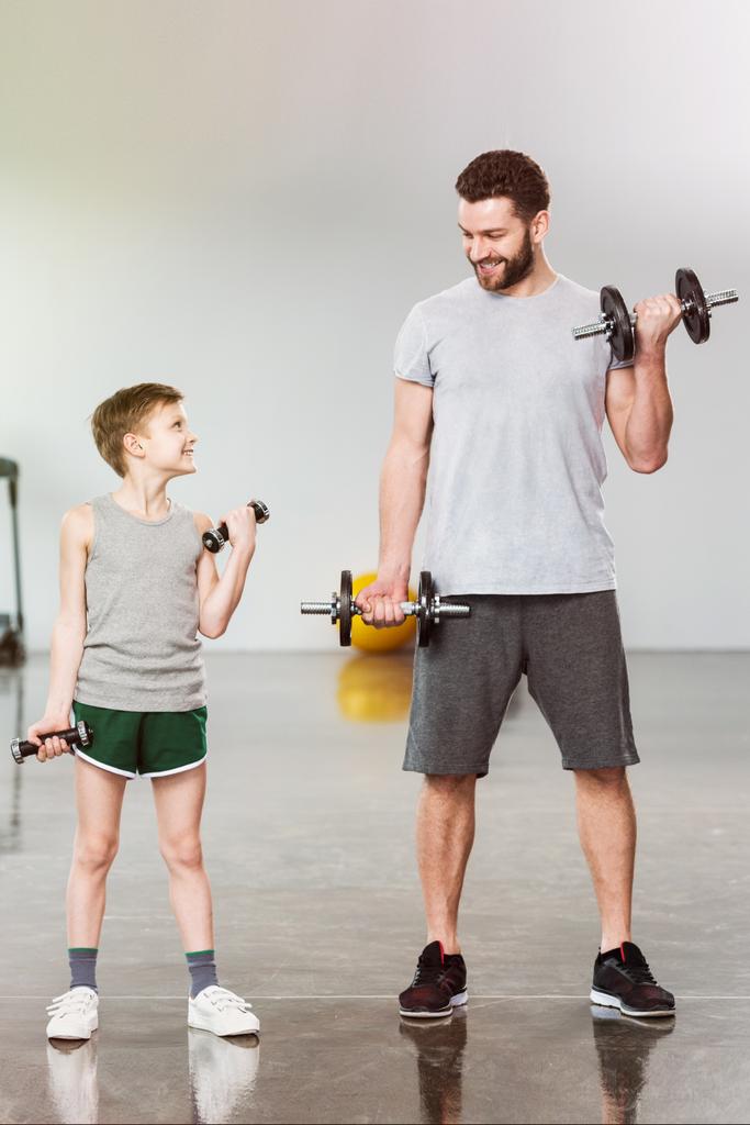 entzückende kleine Kind Training mit Hanteln zusammen mit Vater im Fitness-Center - Foto, Bild