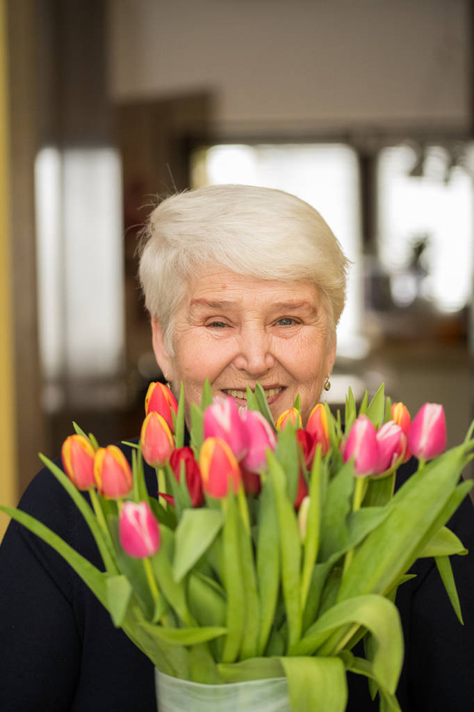 花を持つ高齢者の笑顔の女性 - 写真・画像
