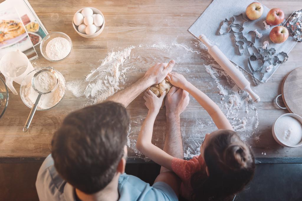 Overhead view of father and daughter kneading dough together - Photo, Image