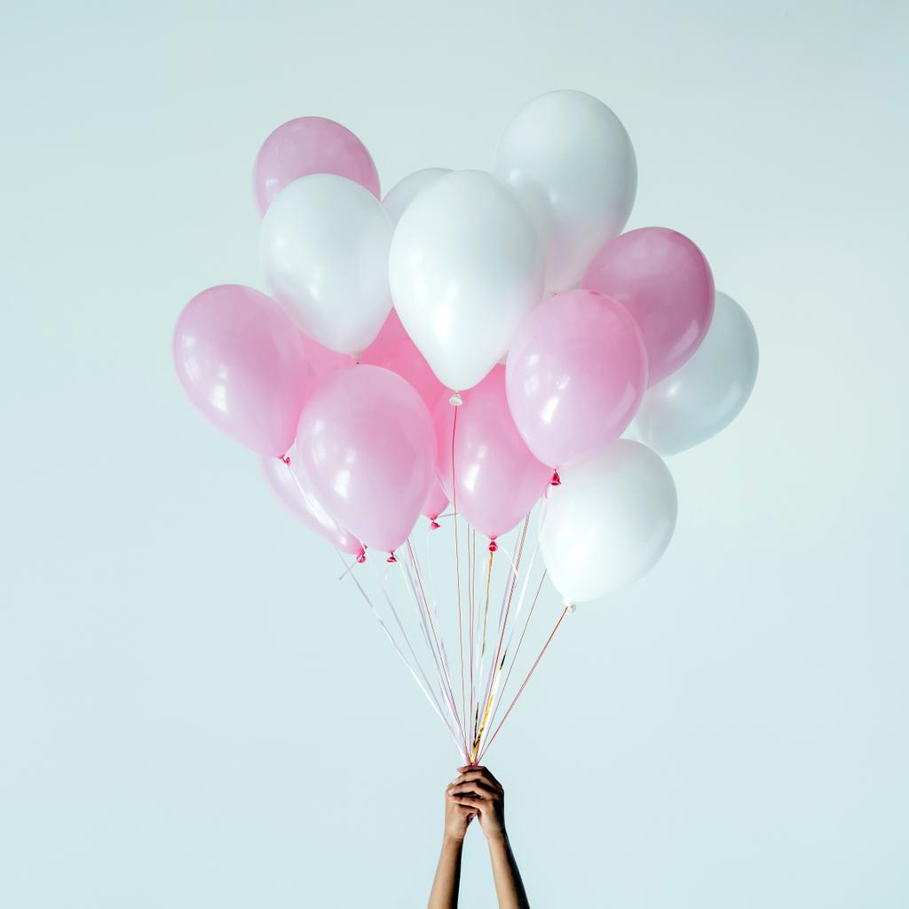 colpo ritagliato di mani che tengono mazzo di palloncini rosa e bianchi isolati su grigio
 - Foto, immagini