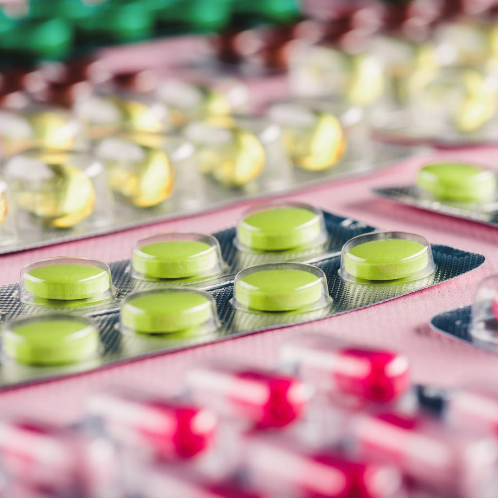 Крупный план различных таблеток в блистерных упаковках на розовом
 - Фото, изображение