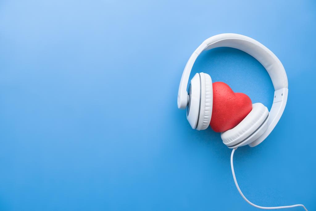 vista superior de fones de ouvido com fio com sinal de coração vermelho no meio na superfície azul
 - Foto, Imagem