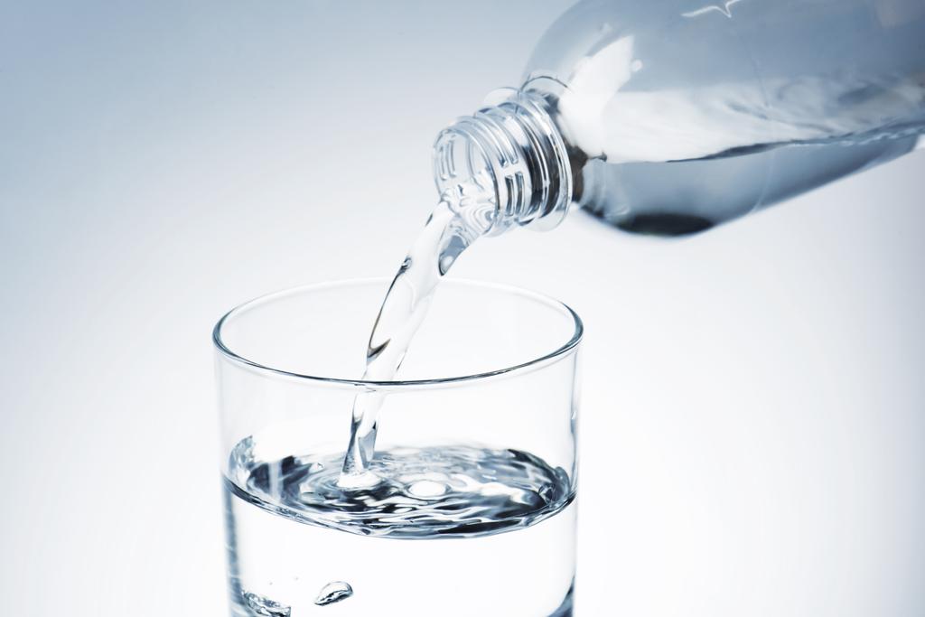 plan rapproché de verser de l'eau de la bouteille en plastique dans le verre
 - Photo, image
