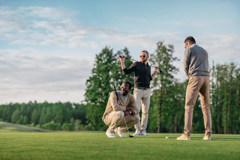 ryhmä nuoria tyylikkäitä monikulttuurisia ystäviä viettää aikaa yhdessä pelatessaan golfia
 - Valokuva, kuva