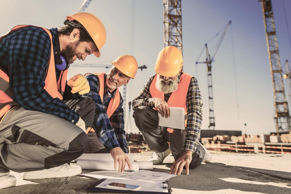 trabalhadores da construção sentados no concreto no canteiro de obras e olhando para os planos de construção
 - Foto, Imagem