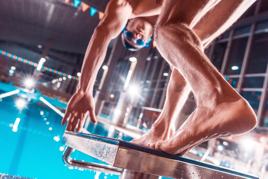 vista dal basso del nuotatore atletico maschile che salta nella piscina da competizione
  - Foto, immagini