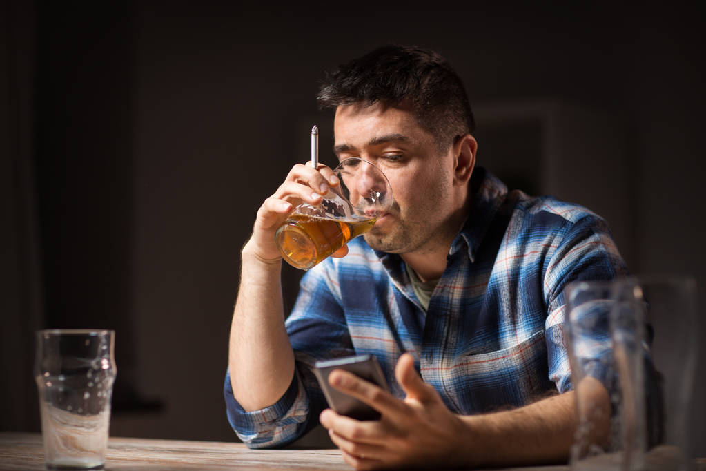 людина з мобільним телефоном п'є алкоголь і курить
 - Фото, зображення