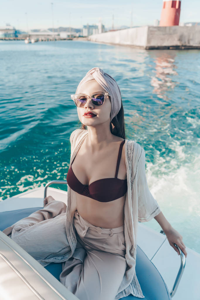 una mujer hermosa rica en gafas de sol corre su yate, unas vacaciones tan esperadas en el mar
 - Foto, imagen