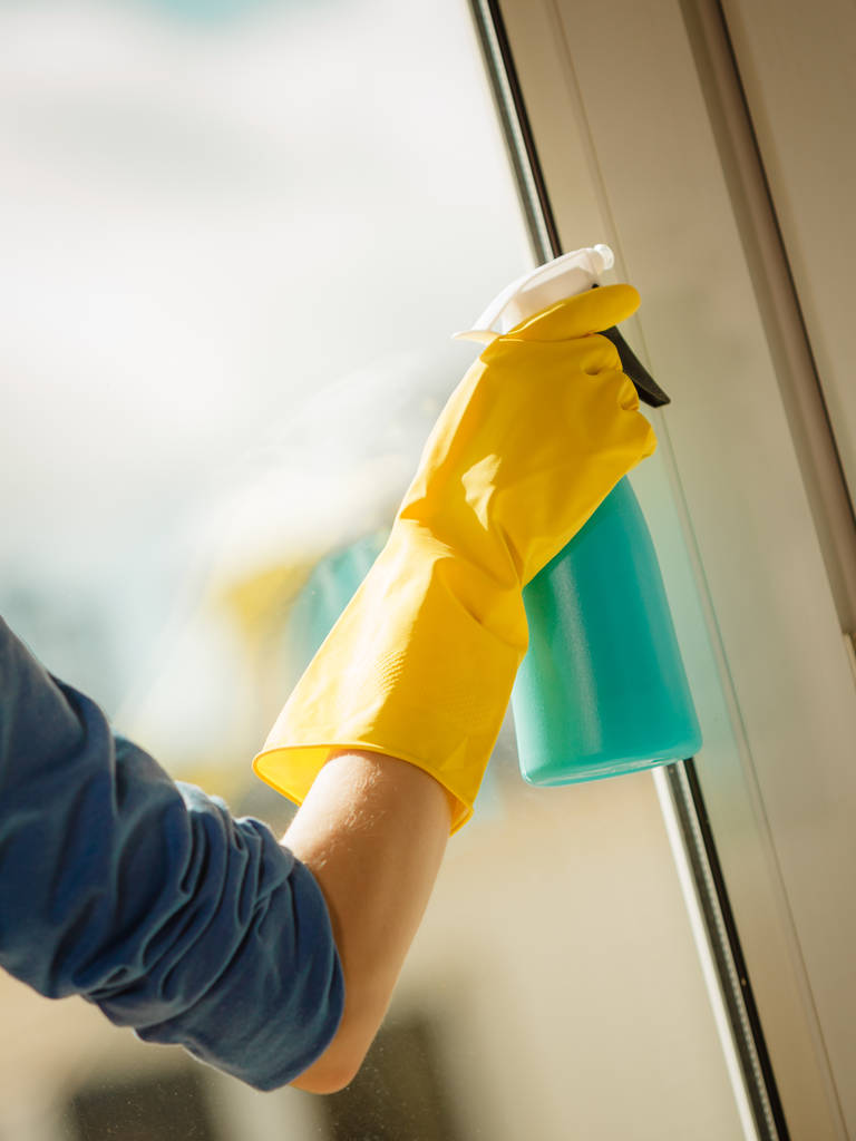 Mão feminina em luvas amarelas janela de limpeza com pano azul e detergente spray. Limpeza de primavera, conceito de trabalho doméstico - Foto, Imagem
