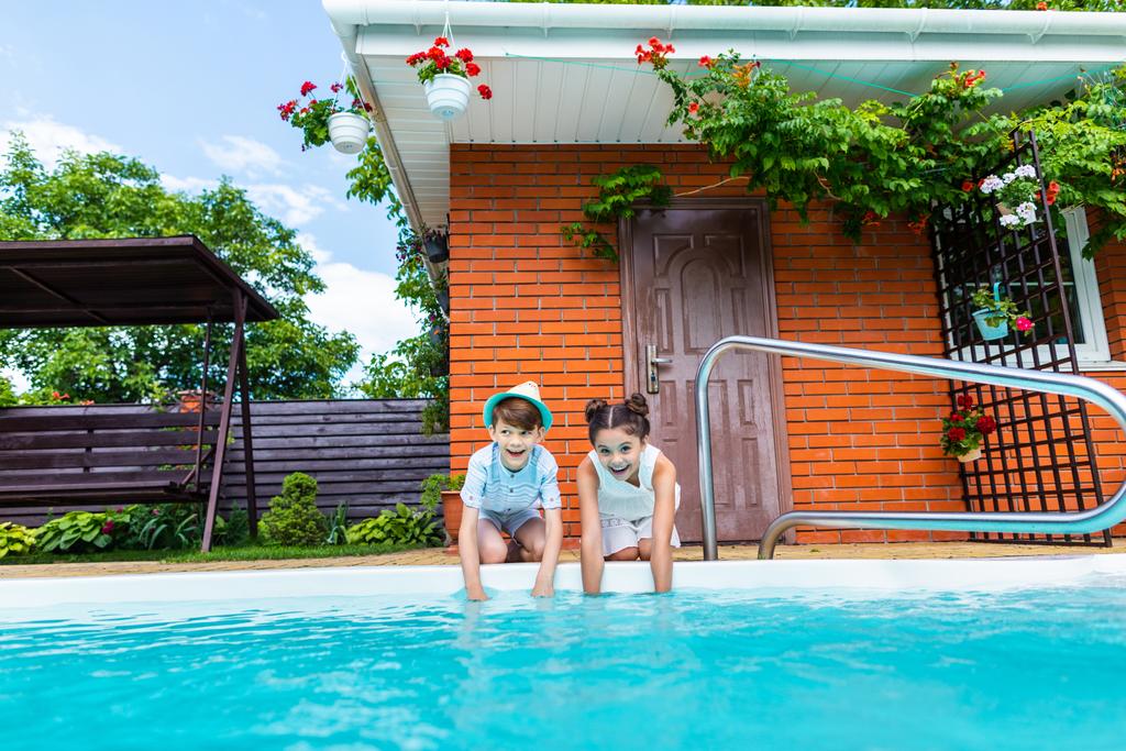 hermanitos sentados cerca de la piscina en el día de verano
 - Foto, imagen