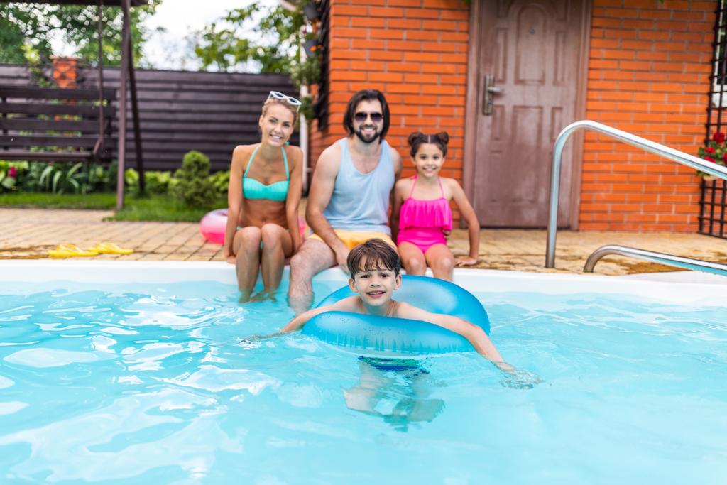 夏の日に田舎の裏庭のプールに近い時間を過ごす幸せな家族の選択と集中 - 写真・画像