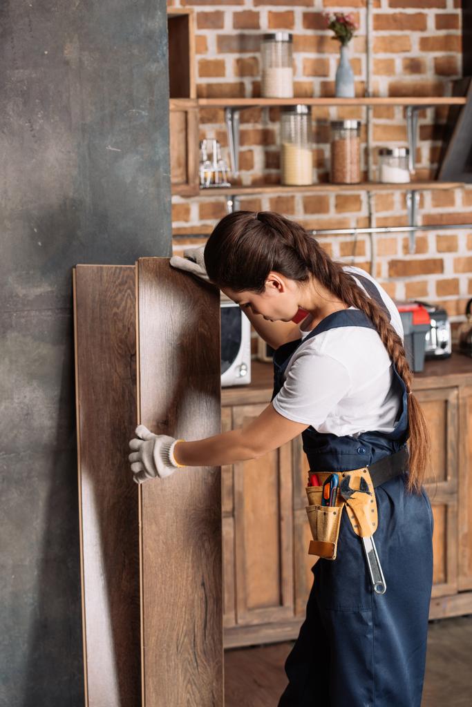 nuori korjaaja nainen työskentelee lattia laminaatti keittiössä
 - Valokuva, kuva