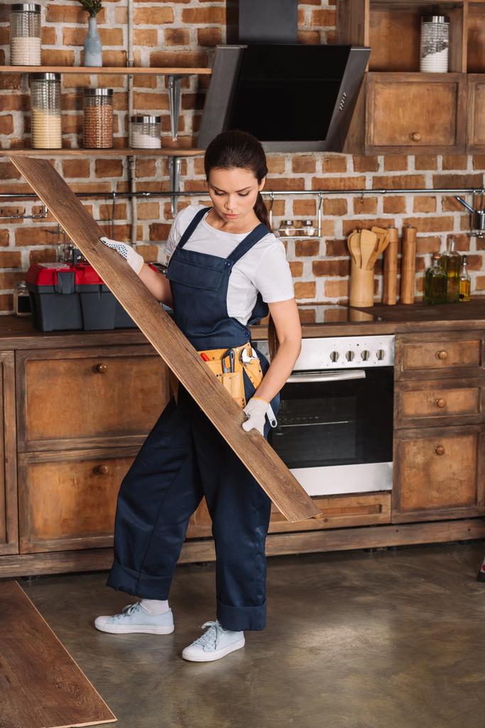 attraktive junge Reparaturfachfrau verlegt Laminat auf Küchenboden - Foto, Bild