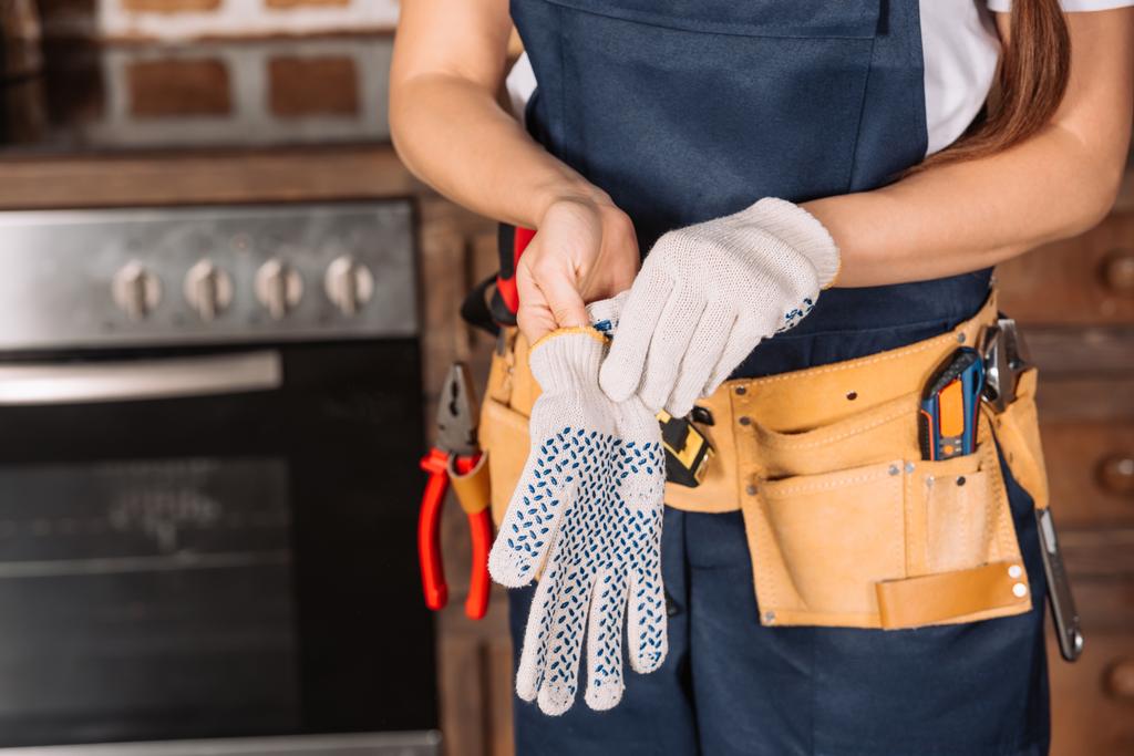 plan recadré de réparatrice portant des gants de travail à la cuisine
 - Photo, image