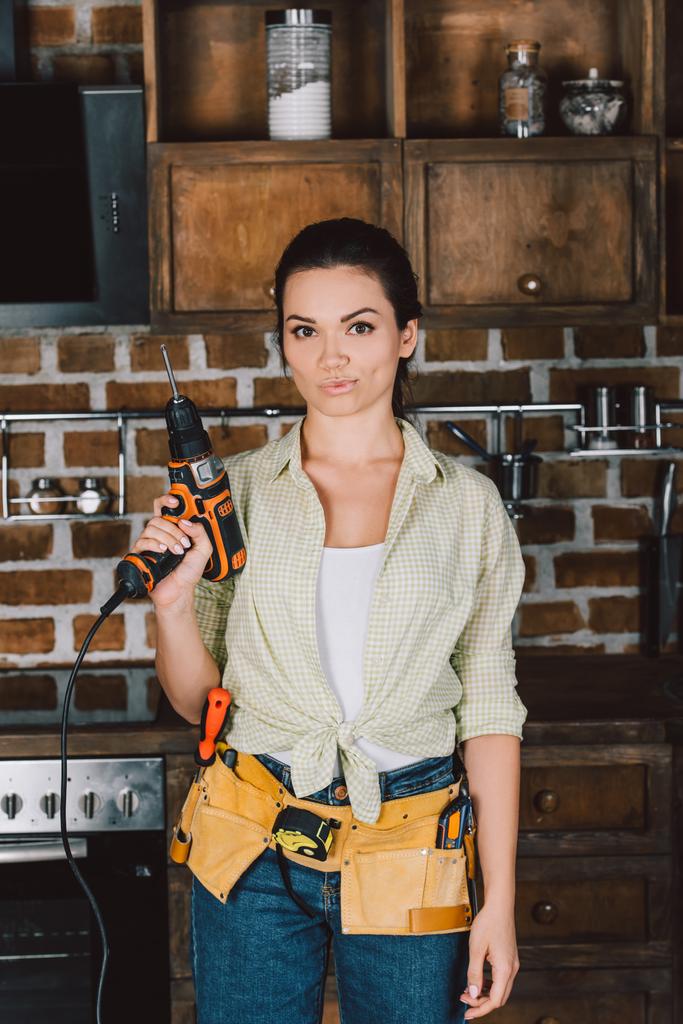 attraktive junge Reparaturfrau mit Bohrmaschine und Blick in die Kamera - Foto, Bild
