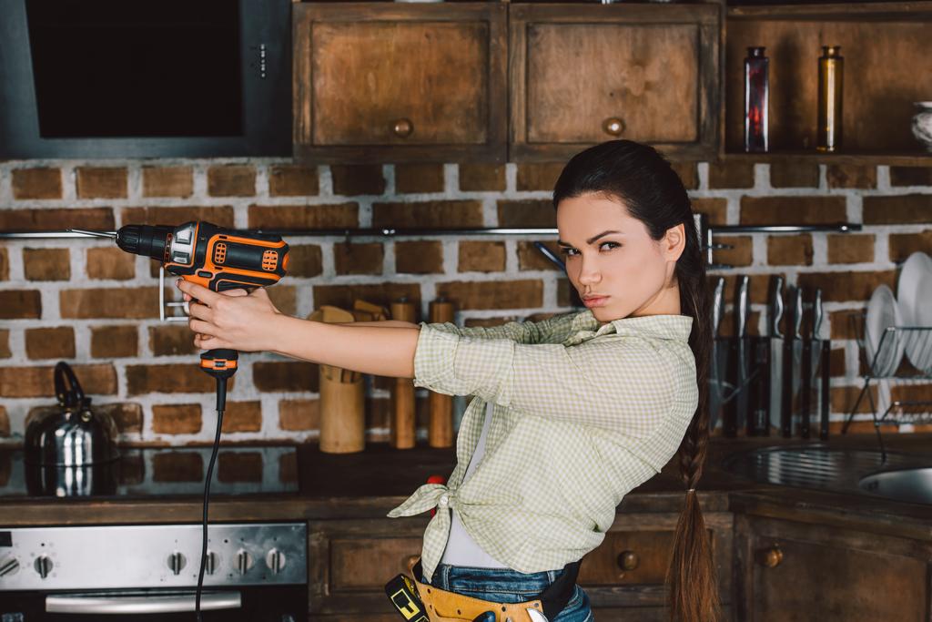 attraente giovane riparatrice tenendo trapano potere come pistola
 - Foto, immagini
