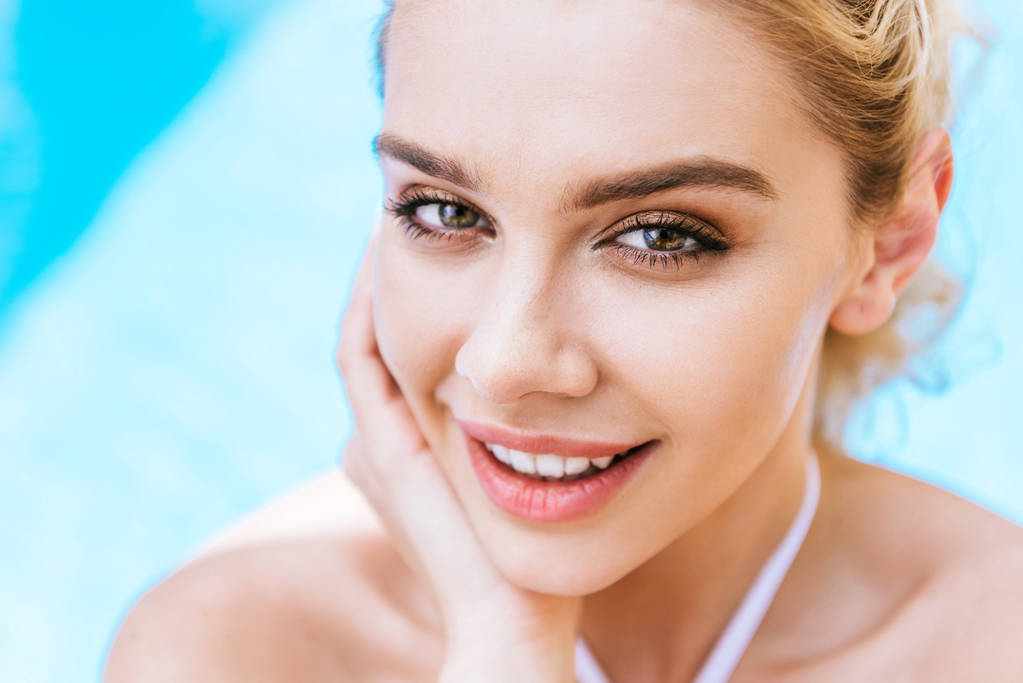 Close-up πορτρέτο του όμορφη νεαρή γυναίκα, που χαμογελά σε κάμερα δίπλα στην πισίνα - Φωτογραφία, εικόνα