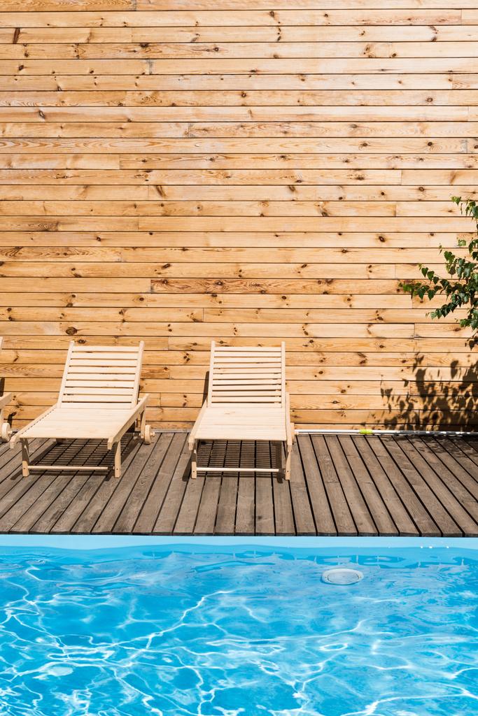 lounges de chaise acolhedores vazios perto da piscina com água transparente
 - Foto, Imagem