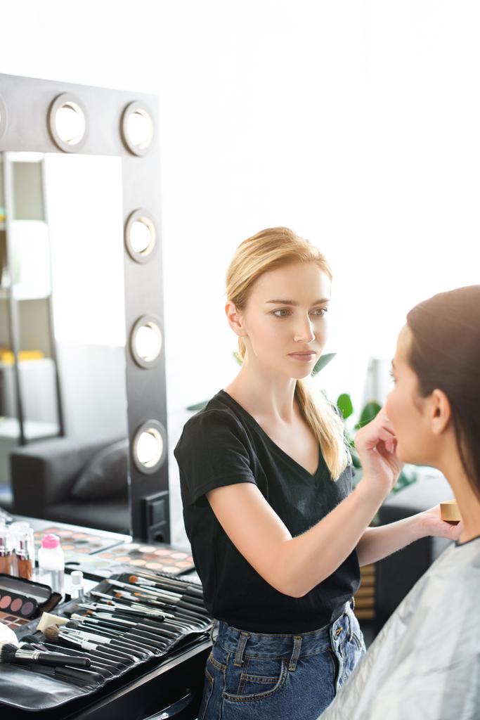 enfoque selectivo de la mujer joven conseguir maquillaje hecho por el artista de maquillaje
 - Foto, imagen