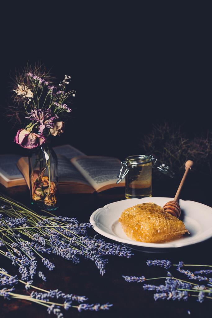 selective focus of lavender, dried flowers and honeycomb on plate on black background  - Photo, Image