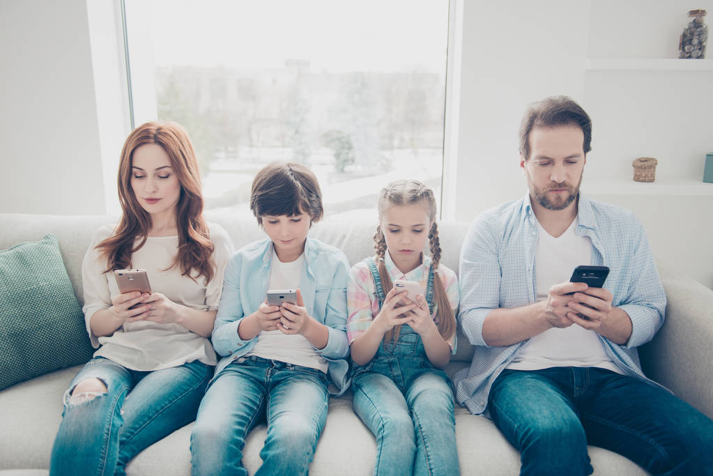Portrait of family with two kids holding smart phones having electronic devices in hands texting sms using wi-fi 3G internet checking email searching contact. Apps concept - Photo, Image