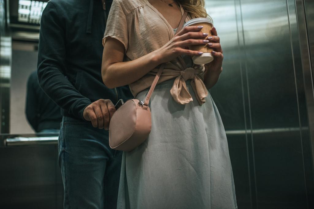 vista ritagliata di furto borseggiando smartphone da donna borsa in ascensore
 - Foto, immagini