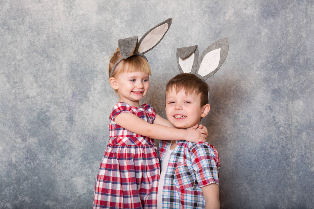 Két gyermek, egy lány és egy fiú a húsvéti nyúl füle fejét nevetni, és játszani. Családi húsvét. Másolja a hely. - Fotó, kép
