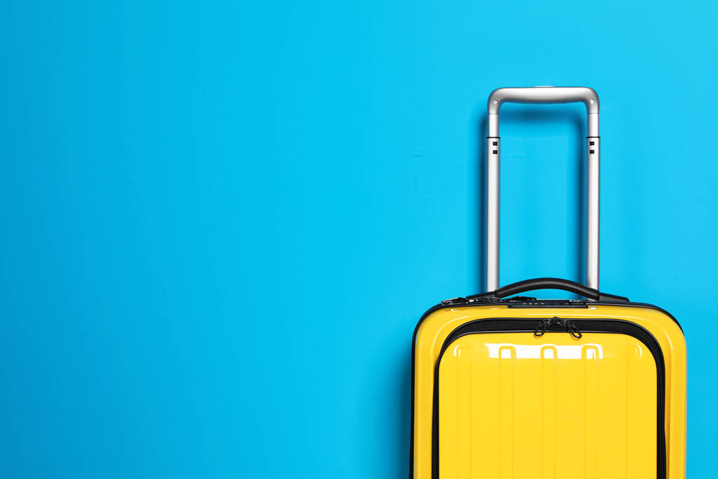 色の背景に明るい黄色のスーツケースを満載 - 写真・画像