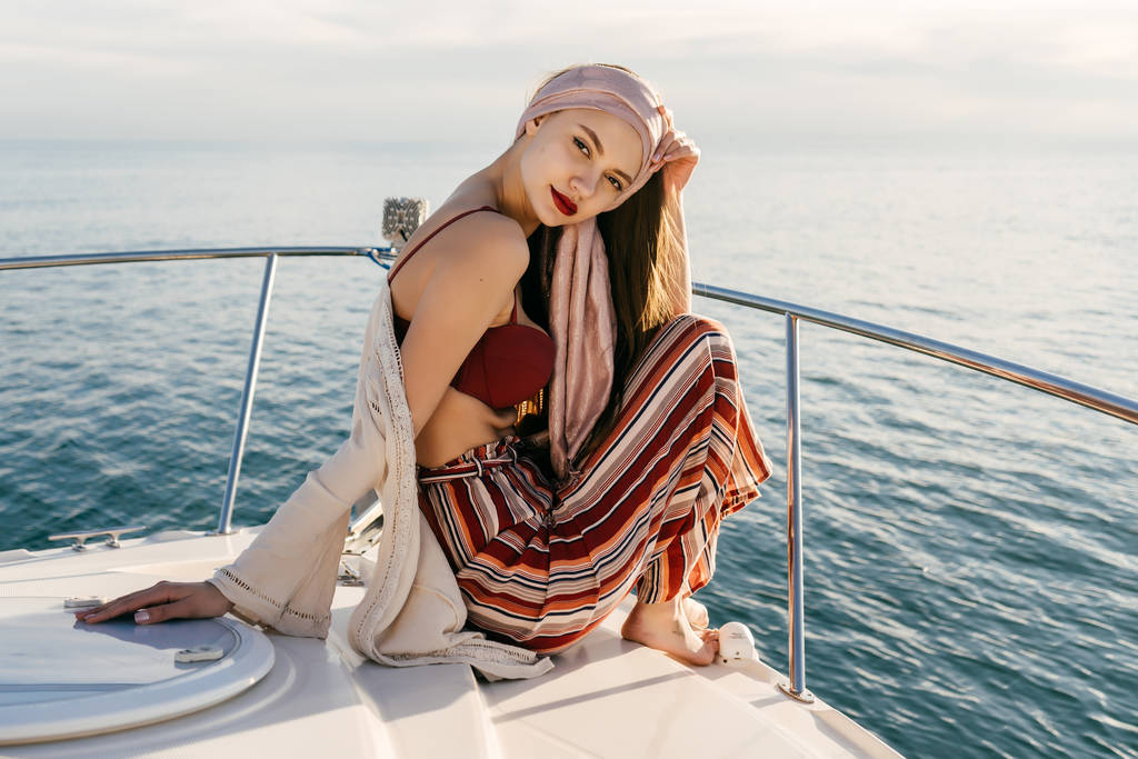 selbstbewusstes, stylisches Mädchen in Sommerkleidung sitzt auf einem Schiff und blickt in die Kamera, segelt auf der Karibik - Foto, Bild