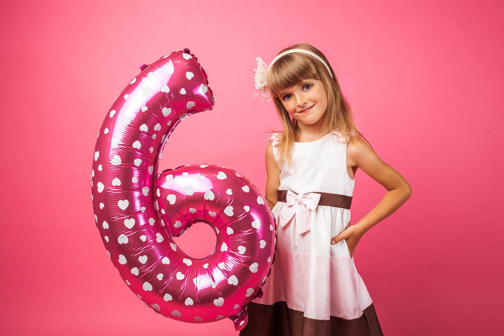 το παιδί κατέχει ένα μπαλόνι στο στυλ των τα ψηφία 6, σε ροζ φόντο στο Studio - Φωτογραφία, εικόνα