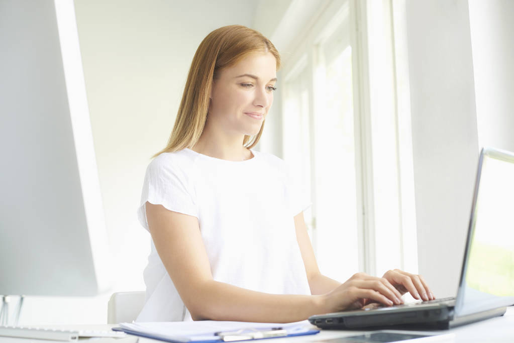 Güzel genç satış kadının modern ofiste yeni proje üzerinde çalışırken dizüstü bilgisayarda yazarak atış.  - Fotoğraf, Görsel