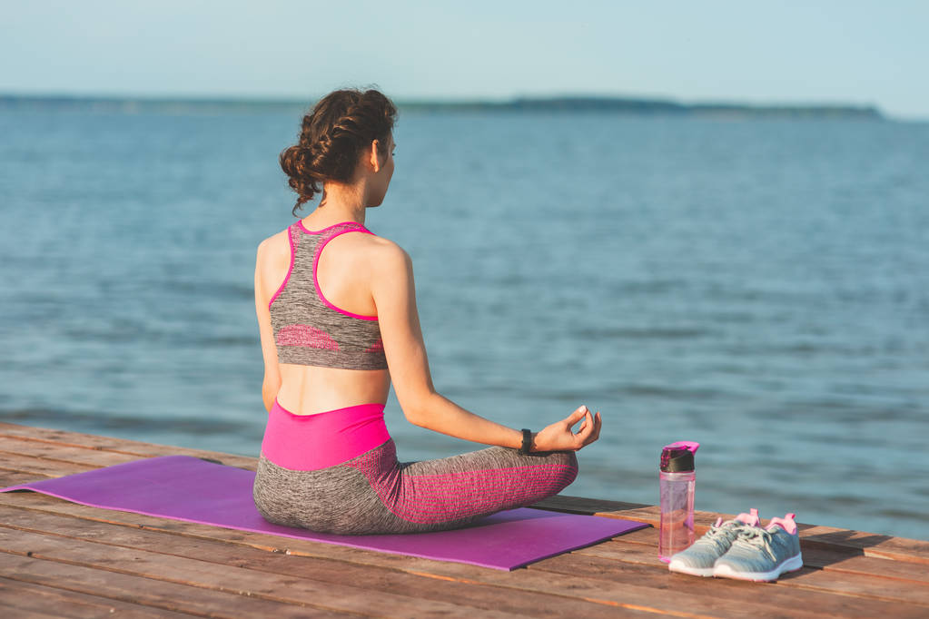 Jeune fille sportive le matin sur le bord de mer, pratiquant le yoga. Femme faire de la gymnastique en plein air. Santé et Yoga Concept
 - Photo, image