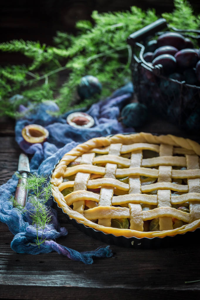 Primer plano de tarta casera con ciruelas en tela azul
 - Foto, imagen
